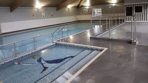 An indoor swimming pool with tiled walls, a clear waterline, and a metal handrail. - Cosy 2 Bedroom Lodge with onsite Pool (Oulton Broad, Lowestoft)