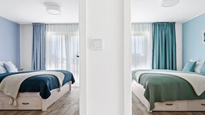 Un dormitorio moderno con cama, mesita de noche y ventana con cortinas.