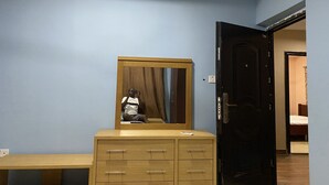 A room with a wooden dresser, a mirror, and a door leading to another room. - Oyibi New Furnished House - Charming 3 Bedroom (Accra)