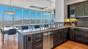 A modern kitchen with dark cabinetry, a granite countertop, and a large window offering a view of the mountains.