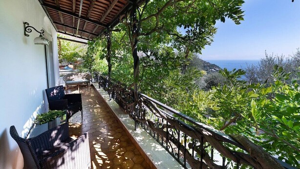 Un espacio al aire libre techado con techo de madera, barandilla y vista al mar.