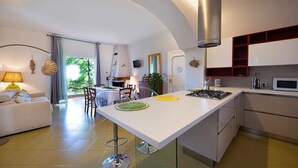 Una cocina moderna con una isla central, muebles blancos y una campana extractora de acero inoxidable.