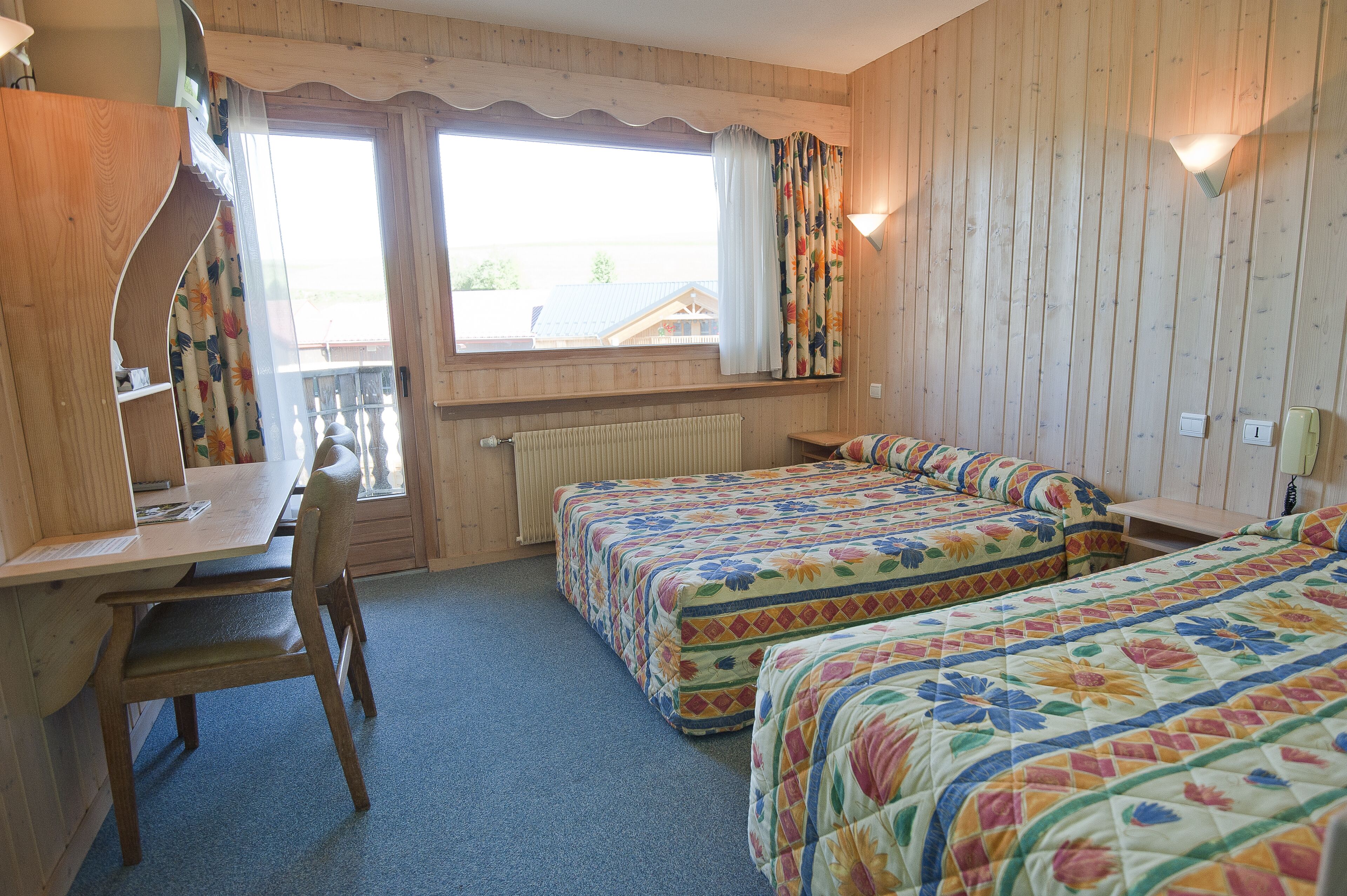 A room with two beds, a desk, and a chair.