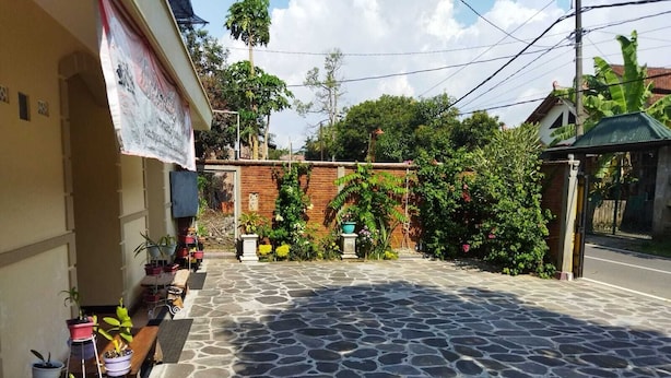 A courtyard with a stone floor, potted plants, and a brick wall.