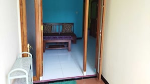 A room with a wooden door, a bench with patterned cushions, and a small white chair.
