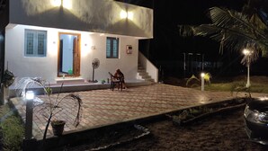 A modern two-story house with a paved entrance, a staircase, and a small outdoor seating area. - wellmark resort room 1, Hall 1,  bathroom 1 (jambavanodai)