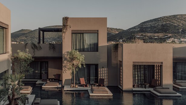 A modern resort with a pool area, outdoor seating, and a view of the surrounding landscape.