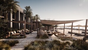 A beachside lounge area with outdoor seating, a large umbrella, and a view of the sea. - Casa Cook Samos (Samos)