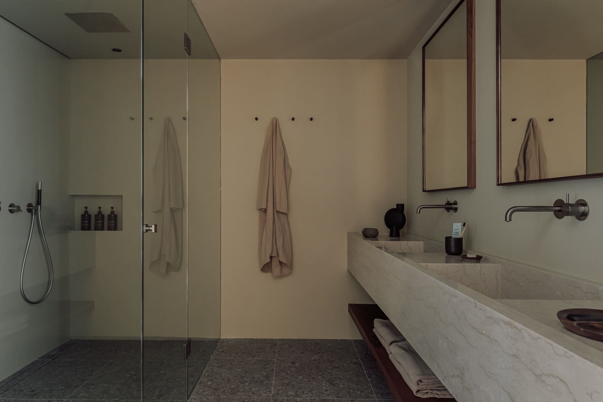 Un bany modern amb una dutxera amb envàs de vidre, un mirall gran i un lavabo de marbre.