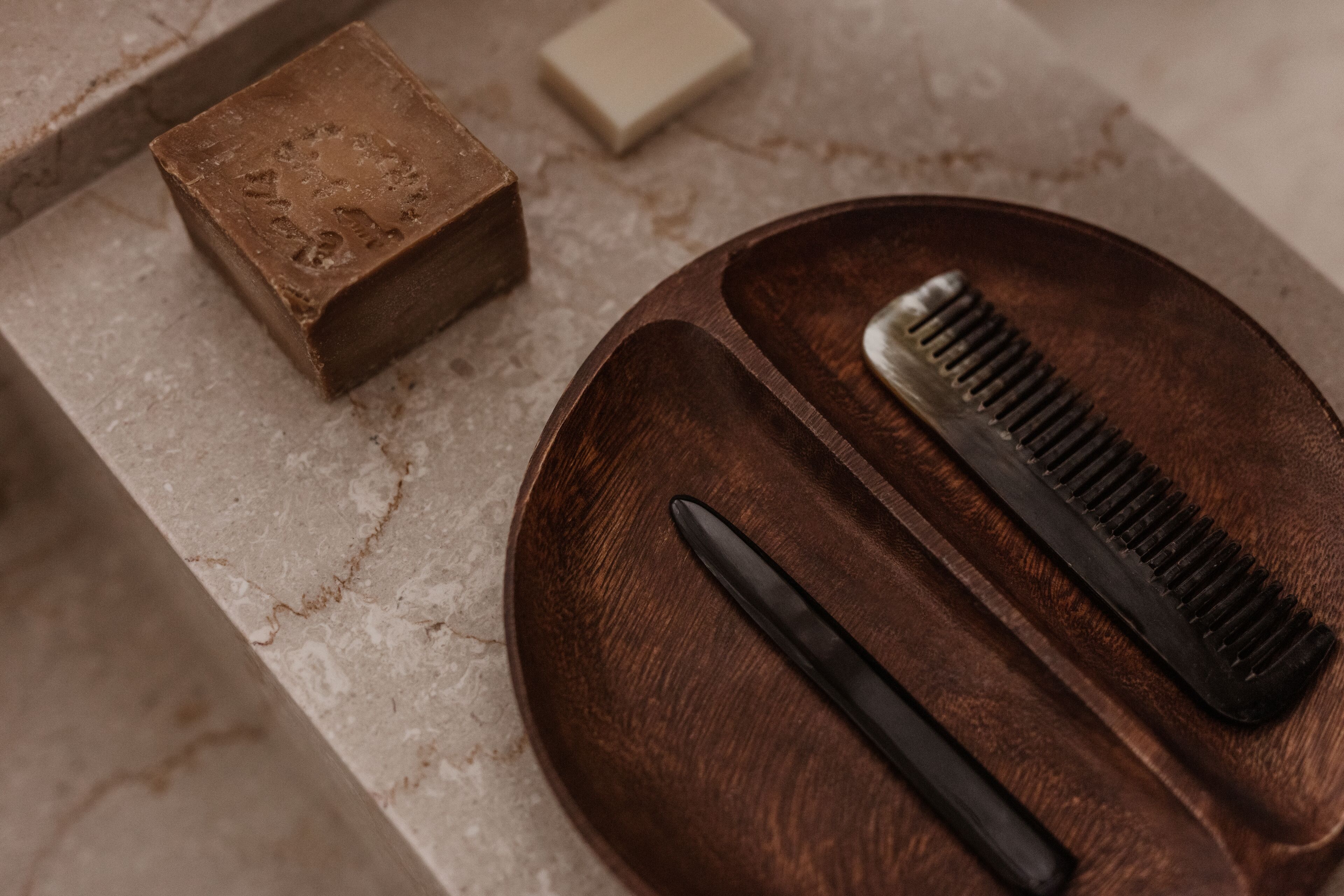 Un plateau en bois avec un peigne et un couteau, posés sur une surface en marbre.