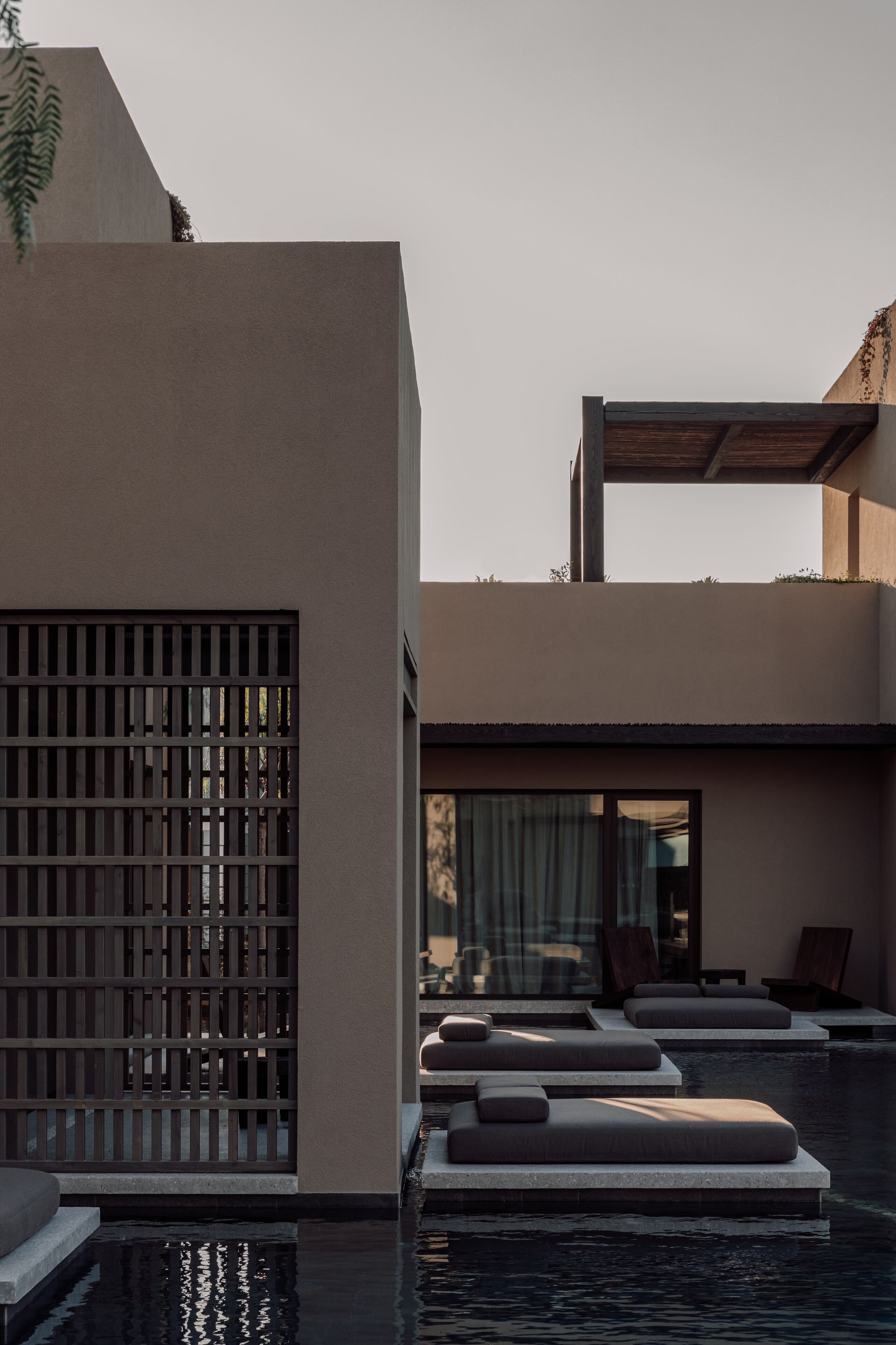 Un área de piscina moderna con asientos escalonados y una pérgola de madera.
