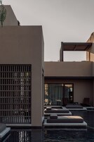 Un área de piscina moderna con asientos escalonados y una pérgola de madera.