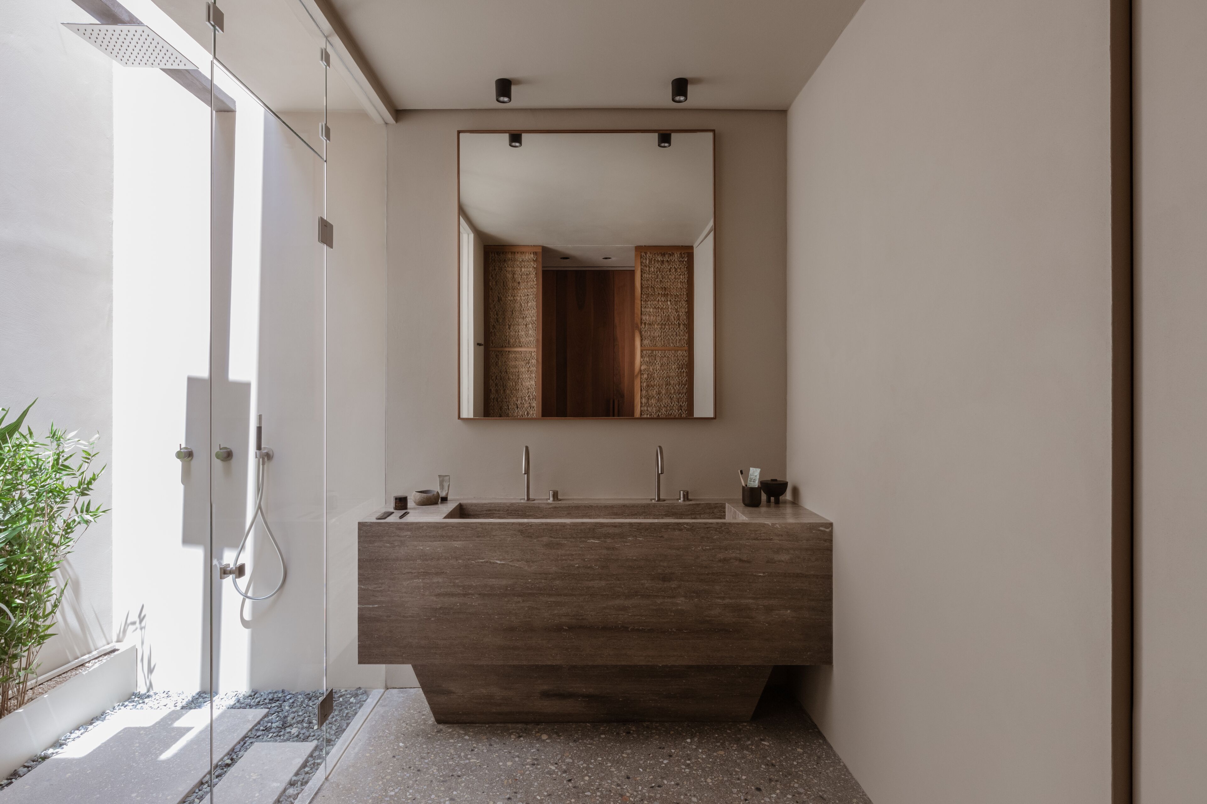 Une salle de bain moderne avec un grand meuble-lavabo en bois, une cabine de douche en verre et un grand miroir au-dessus du lavabo.