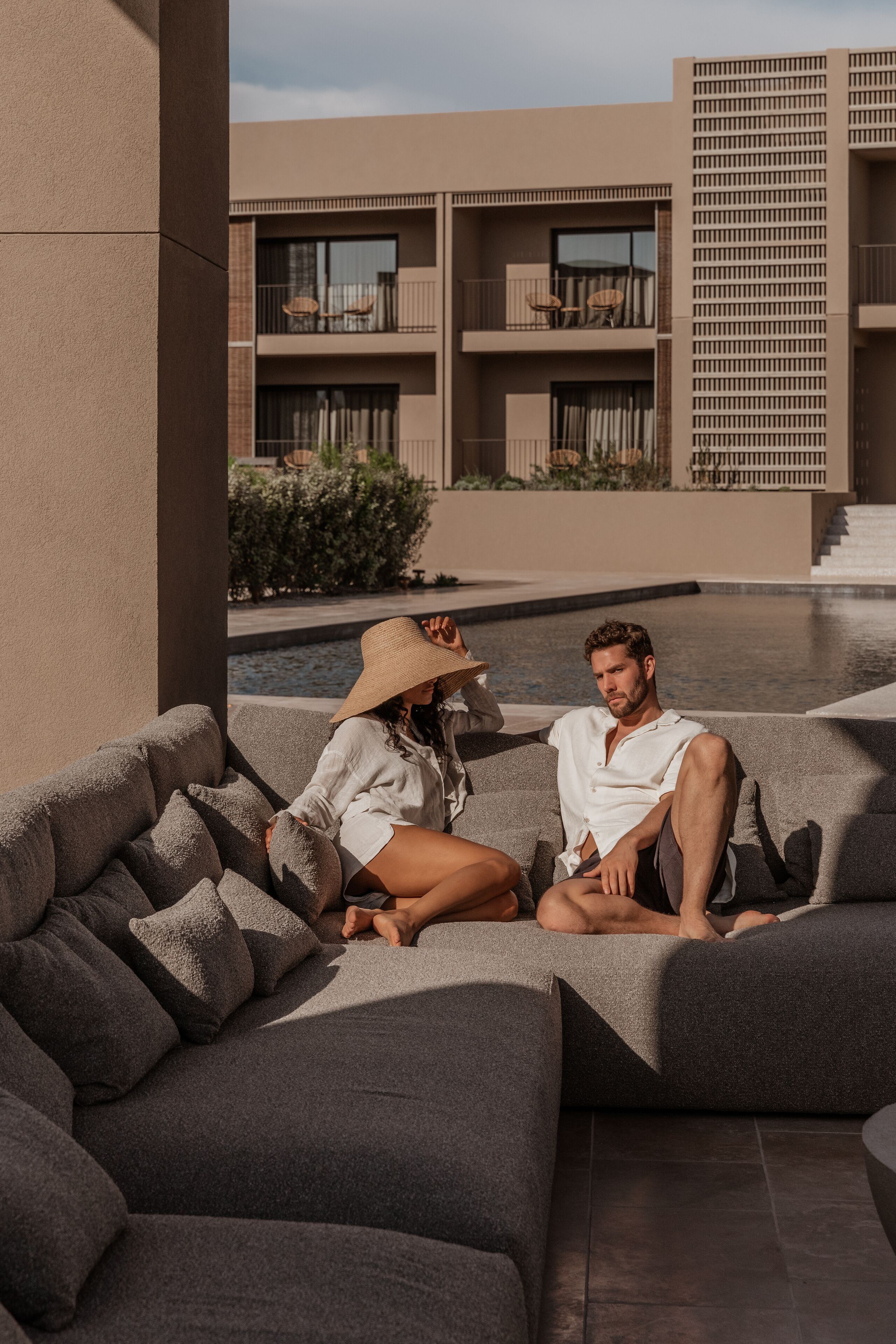 A modern outdoor seating area with a pool and a building in the background.