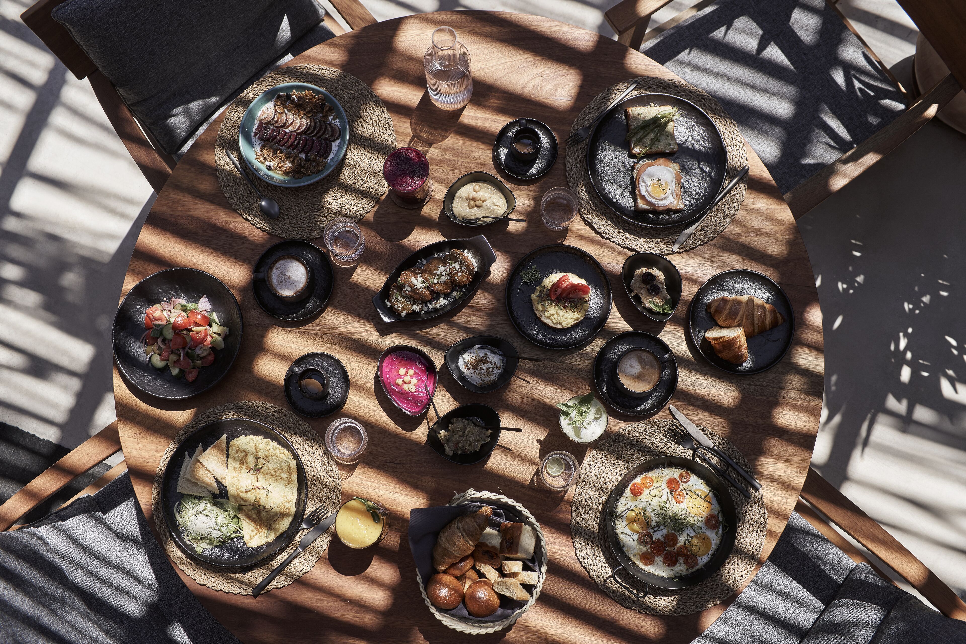 A round wooden table with various dishes and drinks, arranged in a circular pattern.
