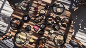 A round wooden table with various dishes and drinks, arranged in a circular pattern.