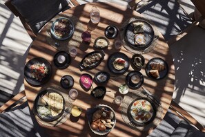 A round wooden table with various dishes and drinks, arranged in a circular pattern.