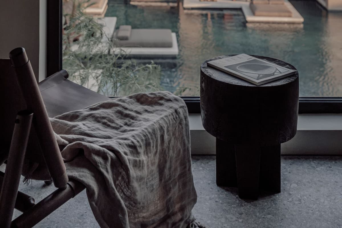 A modern hotel room with a large window overlooking a pool area and a mountain view.