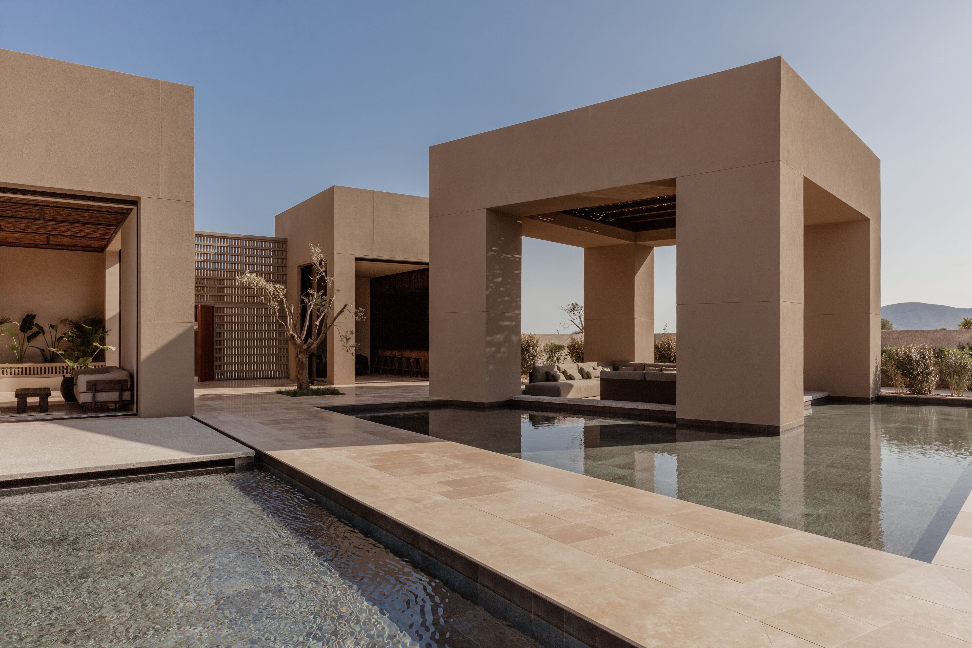 Un área de piscina moderna al aire libre con arquitectura geométrica y mobiliario.