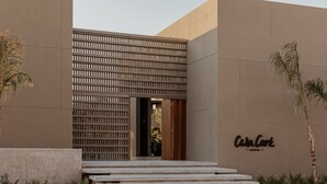 A modern building with a flat facade, a nameplate reading "Casa Corte," and a set of concrete steps leading to the entrance.