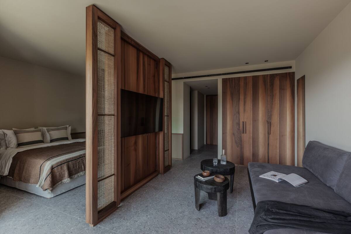 A modern bedroom with a bed, a sofa, a small table, and a wardrobe.