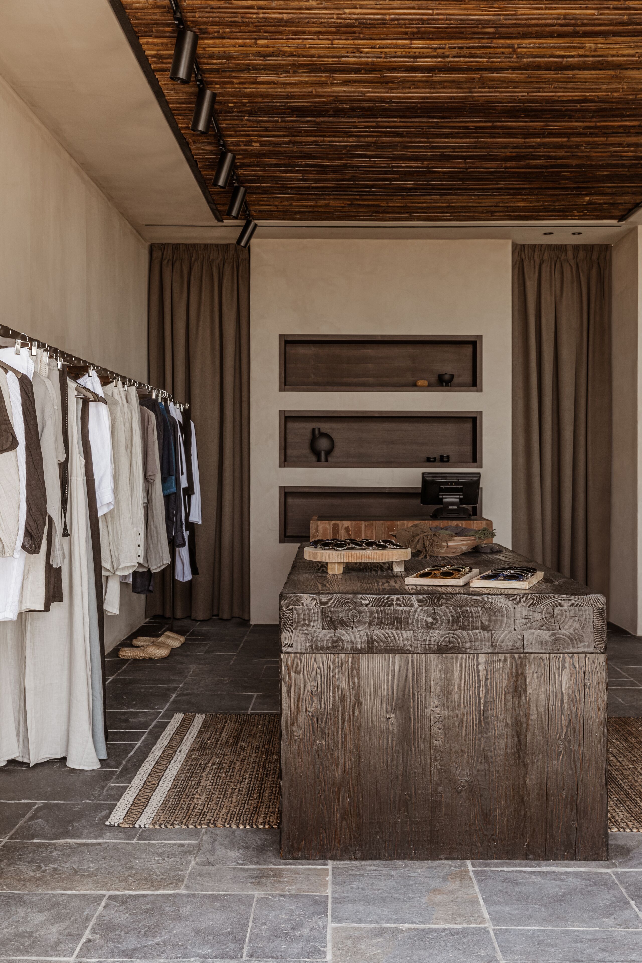 Una habitación con techo de madera, un perchero, un cofre de madera y un estante en la pared con un televisor.