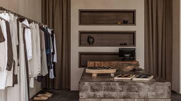 Una habitación con techo de madera, un perchero, un cofre de madera y un estante en la pared con un televisor.