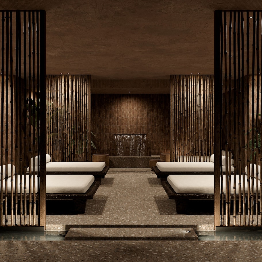 A spa area with two massage tables, a stone floor, and a bamboo partition.