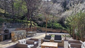 An outdoor patio with wicker furniture, a stone fireplace, and a dining table. - Group offer T3**** + 5 rooms--> 15 people / private interior and garden (Speloncato)