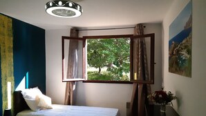 A bedroom with two beds, a window with curtains, a ceiling light, a painting, and a vase with flowers. - Group offer T3**** + 5 rooms--> 15 people / private interior and garden (Speloncato)