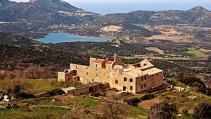 A historic stone building with a courtyard, surrounded by lush greenery and mountains. - Group offer T3**** + 5 rooms--> 15 people / private interior and garden (Speloncato)