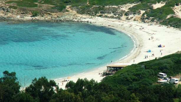 A beach with clear turquoise water, a sandy shore, and a few people and umbrellas. - Group offer T3**** + 5 rooms--> 15 people / private interior and garden (Speloncato)