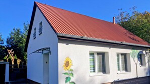 A single-story house with a red roof, a painted sunflower on the side, and a small porch.