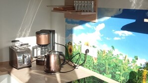 A kitchen with a stove, toaster, kettle, and a wall mural of a sunflower field.