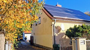 A building with a solar panel roof, a satellite dish, and a gated entrance.