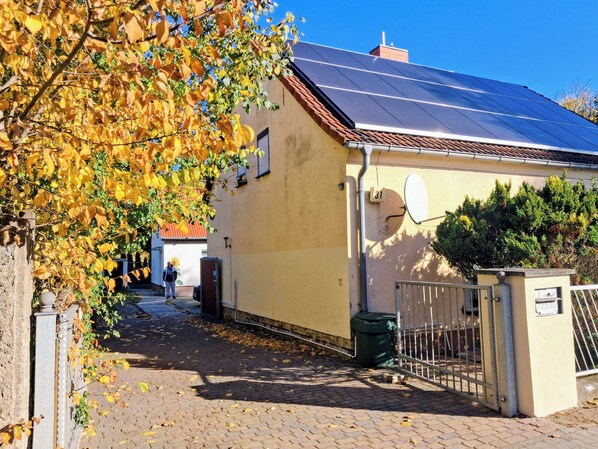 Un bâtiment doté d’un toit recouvert de panneaux solaires, d’une antenne parabolique et d’une entrée sécurisée par un portail.