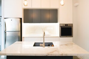 A modern kitchen with a built-in sink, stainless steel appliances, and pendant lighting. - Glyfada Luxury Residence (Glyfada)