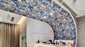 A hotel reception area with a marble-like ceiling, a reception desk, and a glass door leading to a room. - Hinoen Hotel (Taipei)
