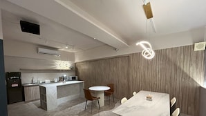 A modern kitchen with a marble countertop, a built-in microwave, and a sink. There is a dining area with a marble table and chairs. - Hinoen Hotel (Taipei)