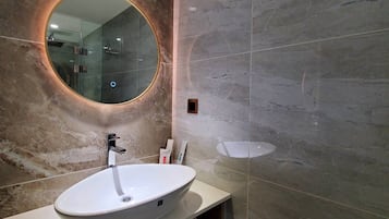 A modern bathroom with a round mirror, a white sink, and a wooden vanity.