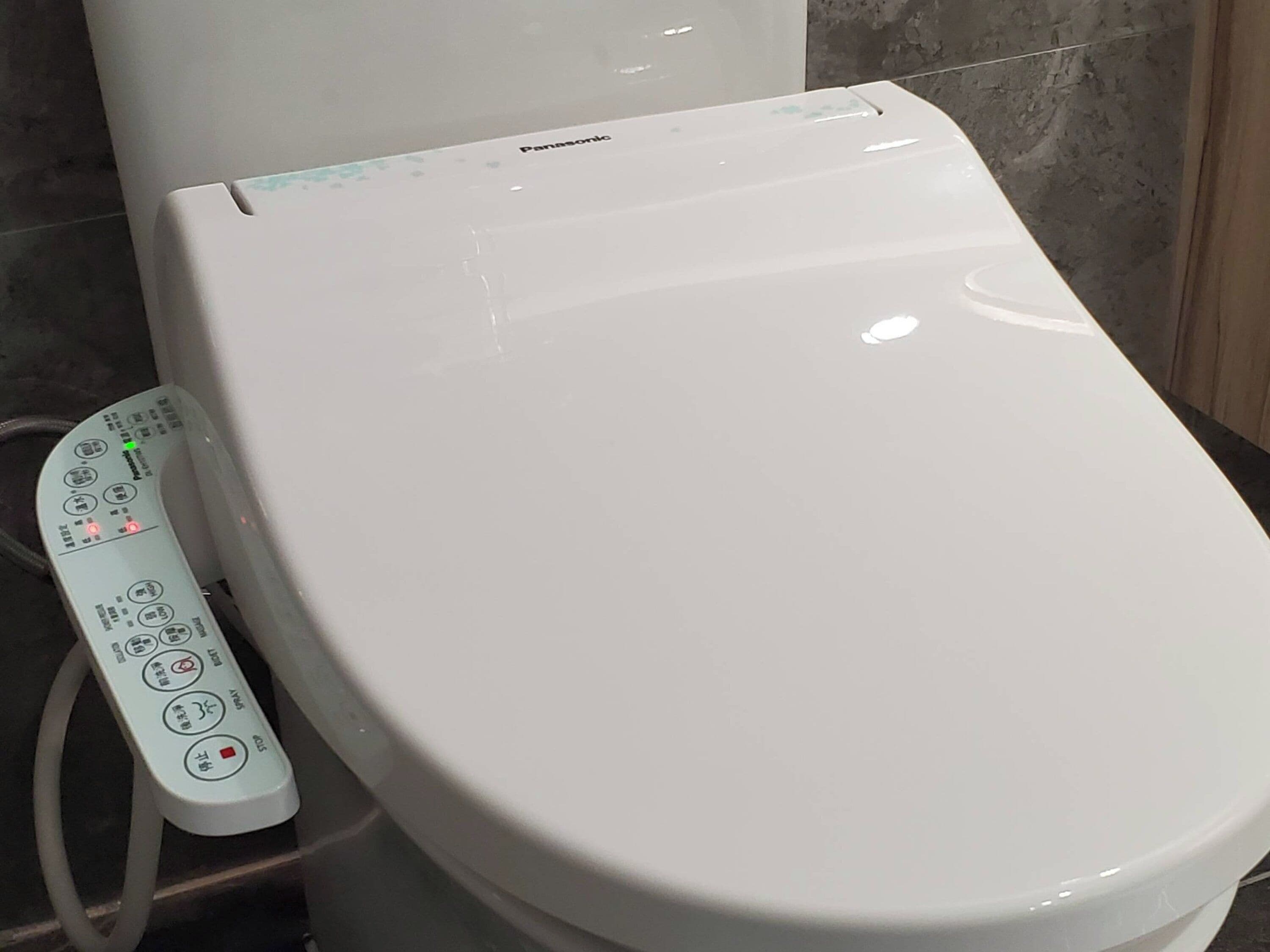 A white toilet with a control panel featuring multiple buttons and a display.
