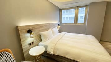 A modern hotel room with a large bed, a small round table, and a houndstooth chair.