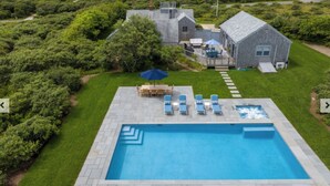Ein rechteckiger Pool mit Whirlpool, umgeben von einer Sonnenterrasse mit Liegestühlen und einem Tisch.