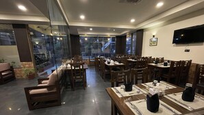 Un restaurante con varias mesas y sillas, ventanas amplias y un televisor de pantalla plana en la pared.
