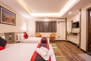 A hotel room with two beds, a television, a painting, and a window with curtains. - Hotel Wawa (Kathmandu)