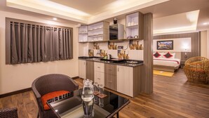 Una habitación de hotel pequeña con kitchenette, comedor y cama.