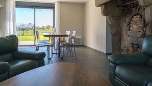 A spacious living area with a dining table and chairs, a fireplace, and a view of the outdoors. - Le Clos de l'Archeneau - Apartment 90m2 - 8 people (Bressuire)