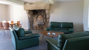 A living room with green leather sofas, a wooden coffee table, and a stone fireplace. - Le Clos de l'Archeneau - Apartment 90m2 - 8 people (Bressuire)