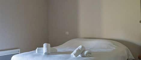 A bedroom with a large bed, wooden beams on the ceiling, and a radiator on the wall.