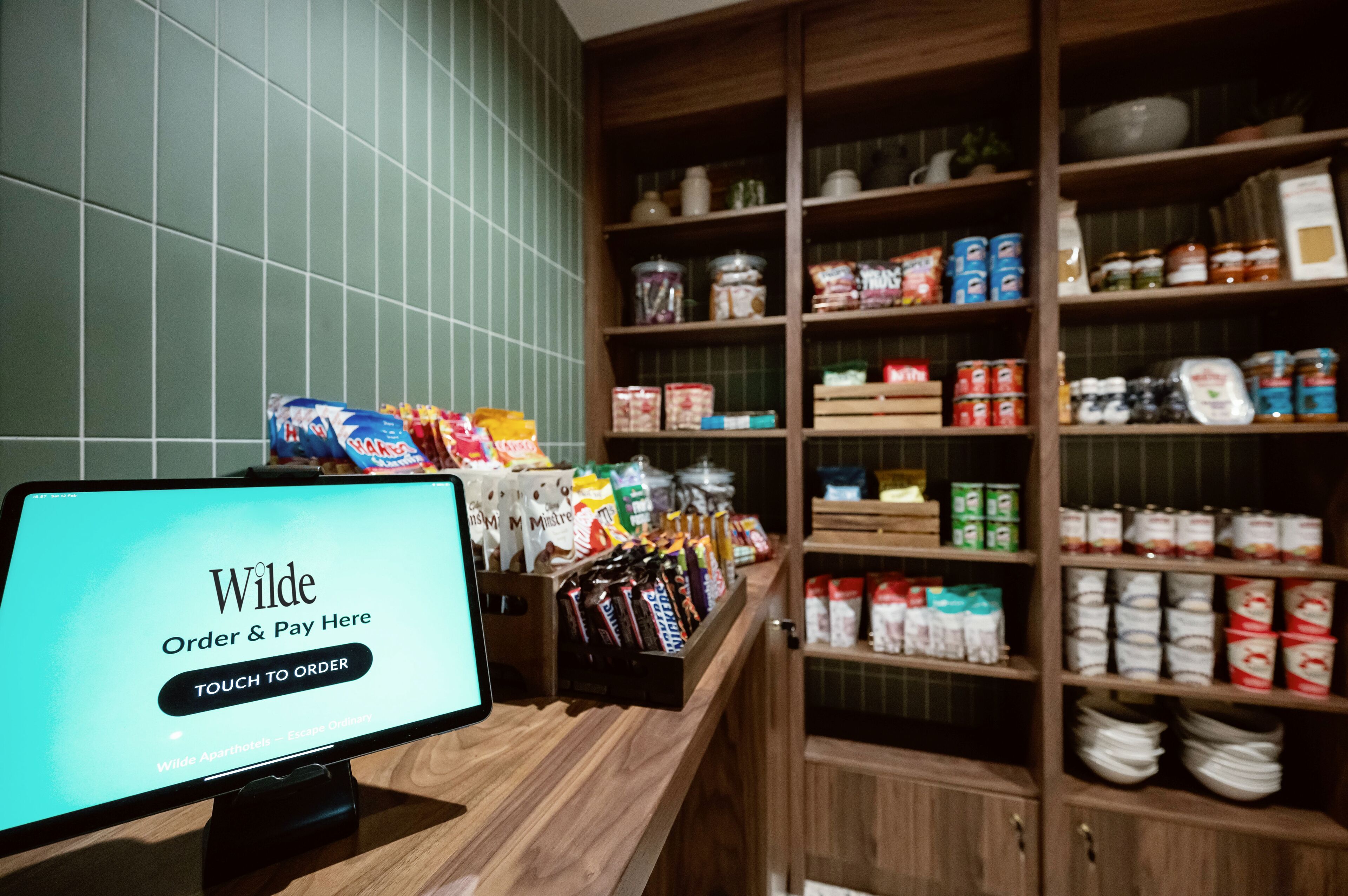 A self-service kiosk with a screen displaying 'Wilde Order & Pay Here' and 'TOUCH TO ORDER'.